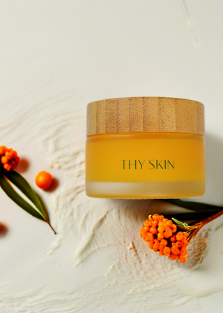 Jar of 'THY SKIN' cream with orange sea buckthorn flowers on a light background 