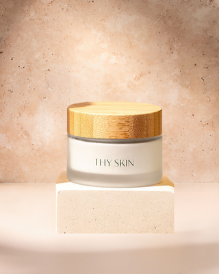 cream in a glass jar with bamboo lid on a marbel